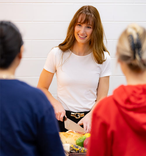 Three students cutting fresh fruit and vegetables